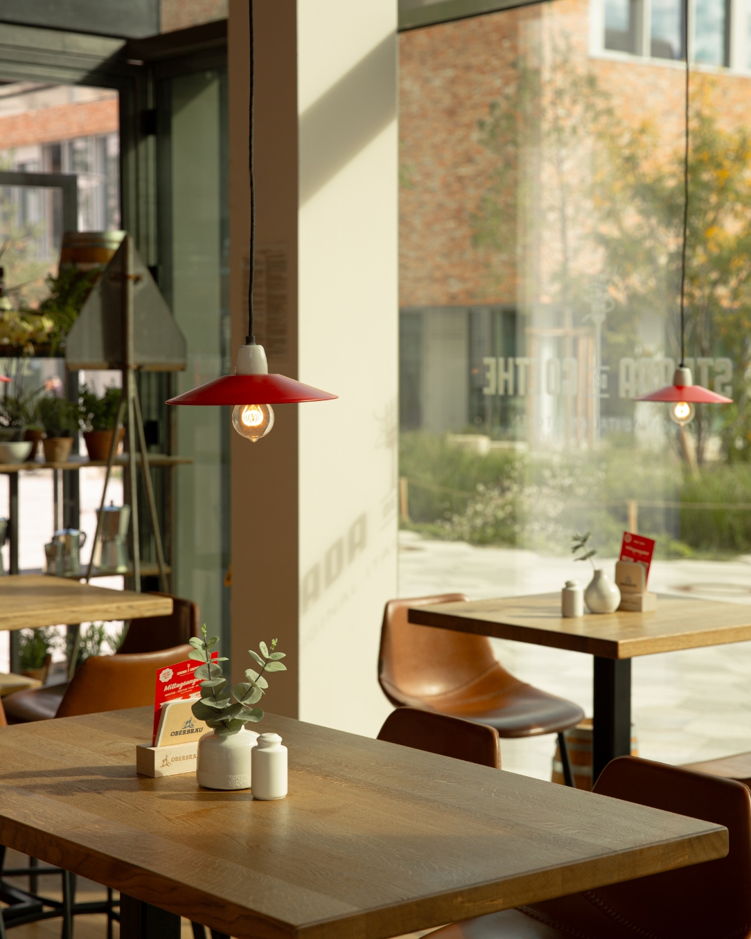 Fensterplatz mit Holztischen und roten Lampen im Strada del Goethe