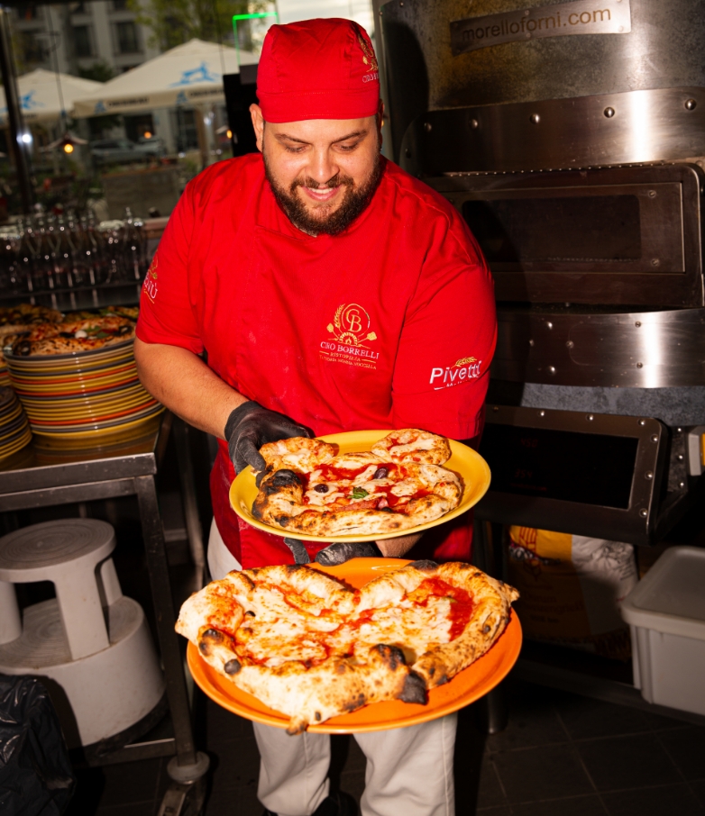 Pizzaiolo mit frisch gebackenen neapolitanischen Pizzen