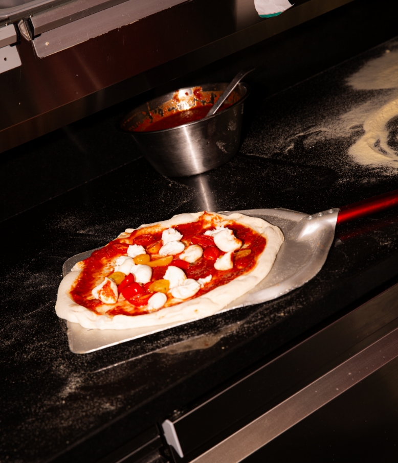 Pizza mit Mozzarella und Kirschtomaten auf der Pizzaschaufel
