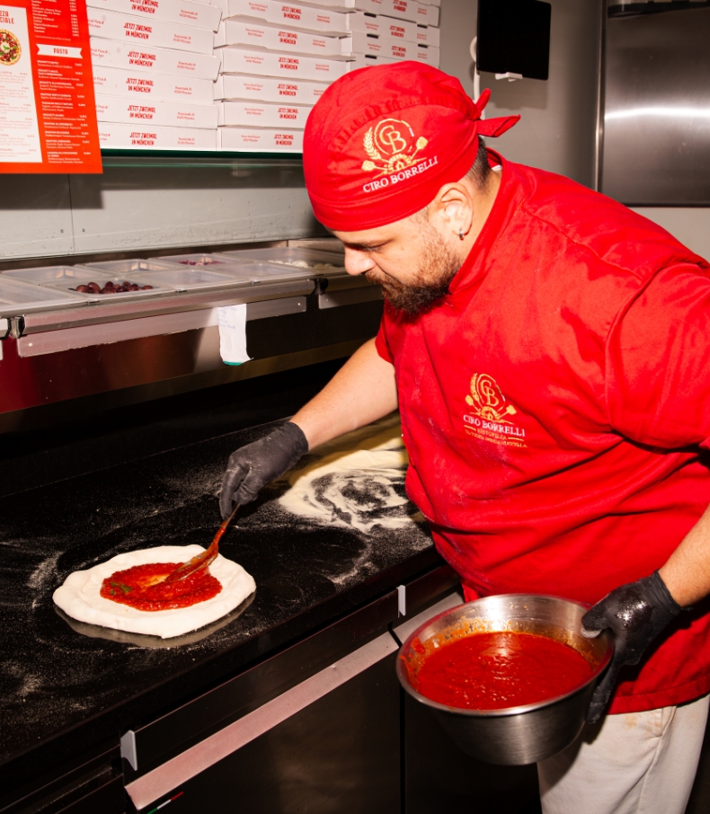 Pizzaiolo bereitet eine Pizza zu