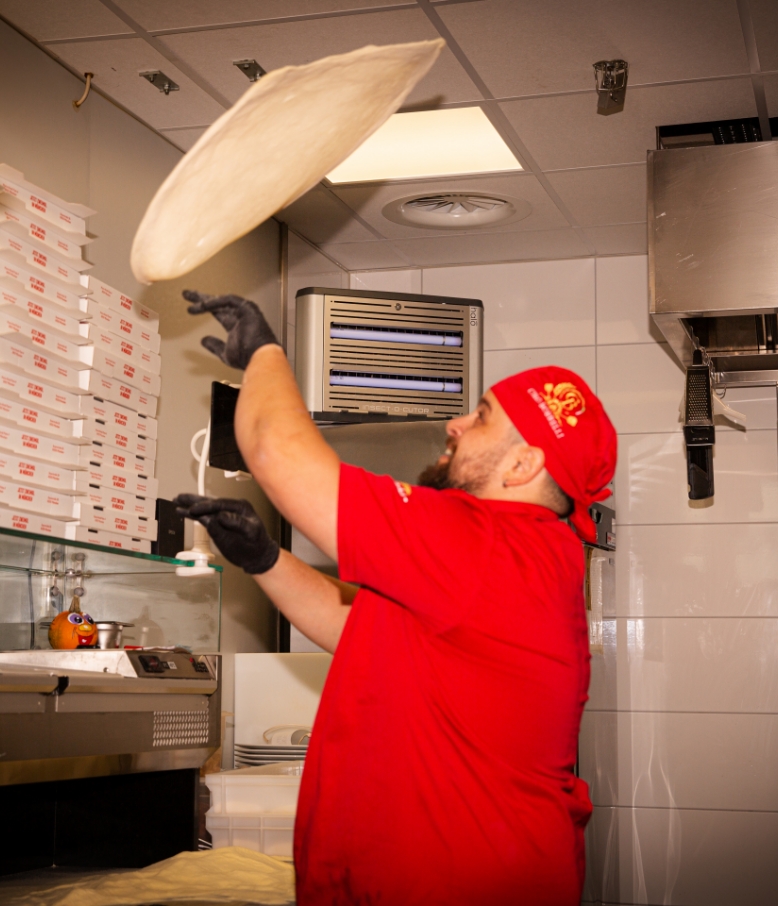 Pizzaiolo wirft Pizzateig in die Luft